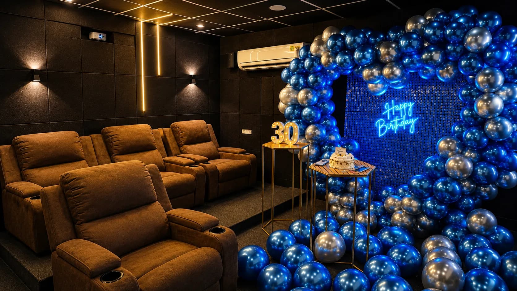 Brown recliner seats in two rows facing a blue and silver balloon arch, with a lit 30 sign, a white cake on a gold stand and a neon Happy Birthday sign on a blue sequin wall